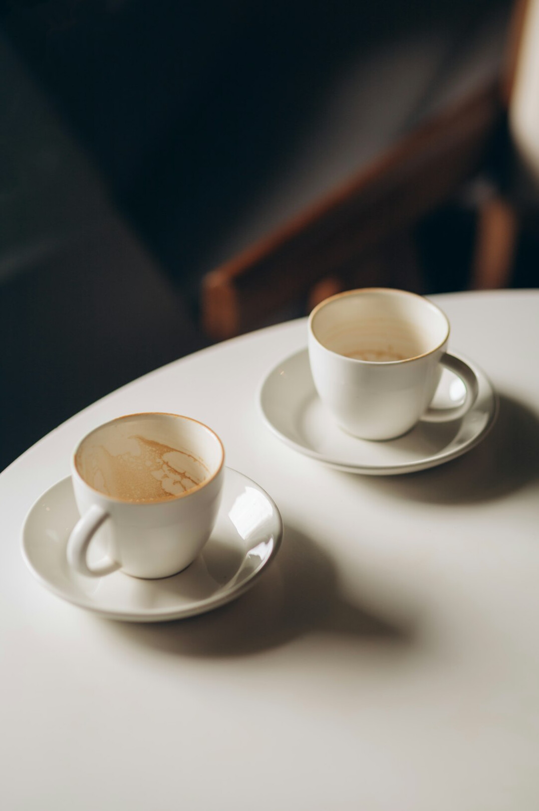 Two coffee cups on a cafe table in soft daylight